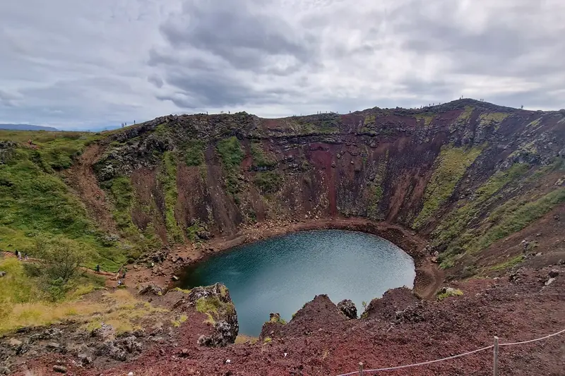 Cráter Kerið con su lago turquesa rodeado de laderas rojizas y verdes