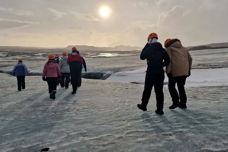 Grupo de viajeros con ropa de abrigo caminando por la nieve al atardecer