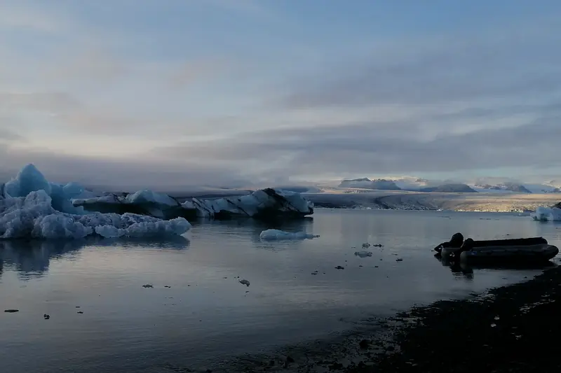 Laguna glaciar de Jökulsárlón al atardecer con icebergs y una lancha en la orilla