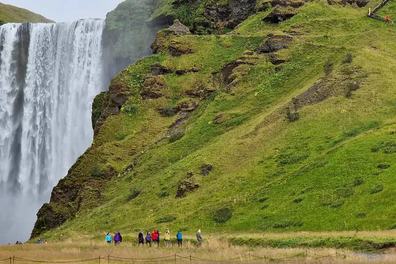 Cascada Skógafoss en verano, rodeada de prados verdes